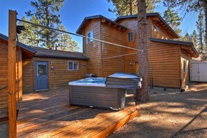 A wooden cabin with a hot tub, deck, and a covered area.