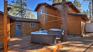 A log cabin with a hot tub, wooden deck, and a garage.