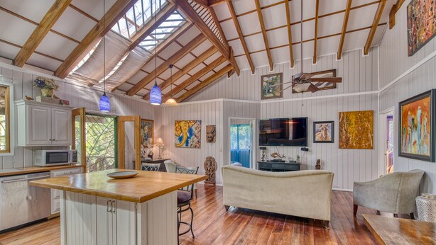 A spacious living area with a wooden ceiling, a television, and various artworks. - Apartment by the Caribbean sea. 4 min walk from the beach! Air-conditioning! (Limón Province)