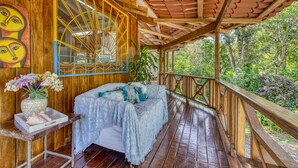 A wooden deck with a bed, a vase of flowers, and a painting on the wall. - Apartment by the Caribbean sea. 4 min walk from the beach! Air-conditioning! (Limón Province)