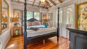 A four-poster bed with a canopy, wooden flooring, and a ceiling fan. - Apartment by the Caribbean sea. 4 min walk from the beach! Air-conditioning! (Limón Province)