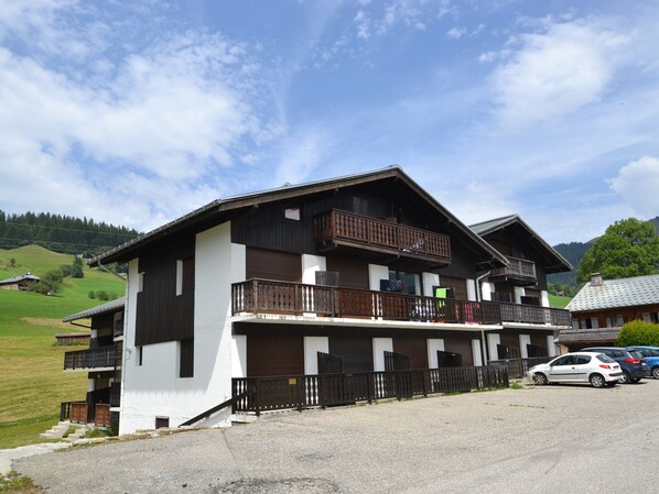A two-story building with a balcony on the upper floor, a garage, and a parking area with cars. - Renovated studio near slopes for 4 (Notre-Dame-de-Bellecombe)