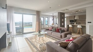 Ein modernes Wohnzimmer mit einer Couch, einem Couchtisch und Blick ins Freie.