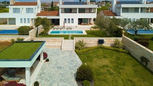 Ein modernes, zweistöckiges Haus mit Swimmingpool, einem gepflegten Rasen und einem Kiesweg zum Eingang.