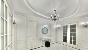 A spacious room with a marble floor, a chandelier, a white vanity with a mirror, and a black ottoman. - Home Apart Sverdlova str 26 (Minsk)