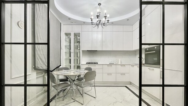 A modern kitchen with white cabinets, a dining table with chairs, and a chandelier. - Home Apart Sverdlova str 26 (Minsk)