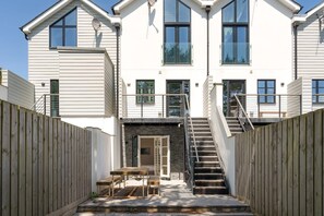 A two-story building with a central entrance, a staircase, and a small outdoor seating area.