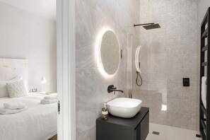 A modern bathroom with a white sink, a mirror, and a shower.