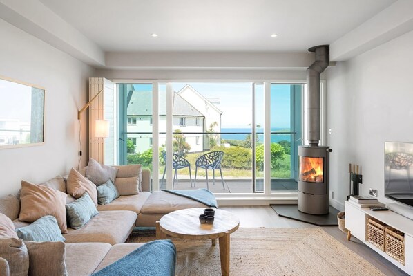 A modern living room with a sofa, a round coffee table, a fireplace, and a TV.
