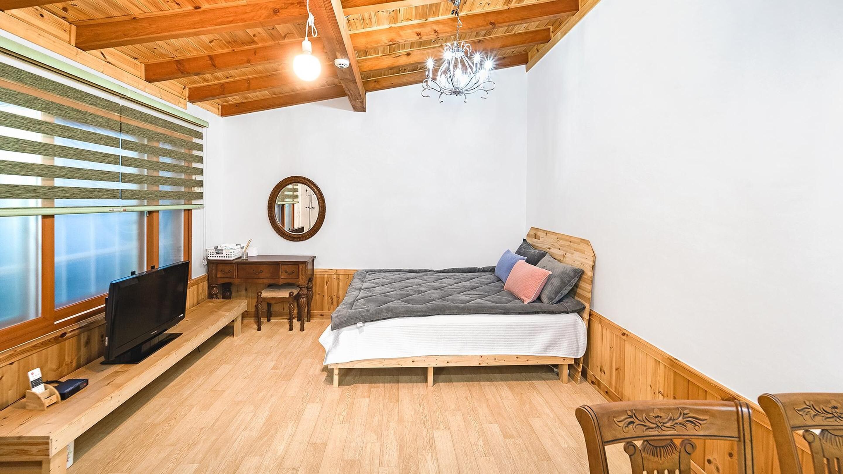 Een gezellige kamer met een bed, houten meubels, een televisie en een kroonluchter.