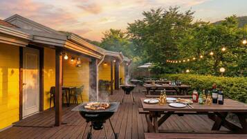 An outdoor patio with a barbecue grill, dining tables, and chairs.