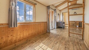 Ett rum med träpanel på väggarna, en säng, ett skrivbord och en stege.