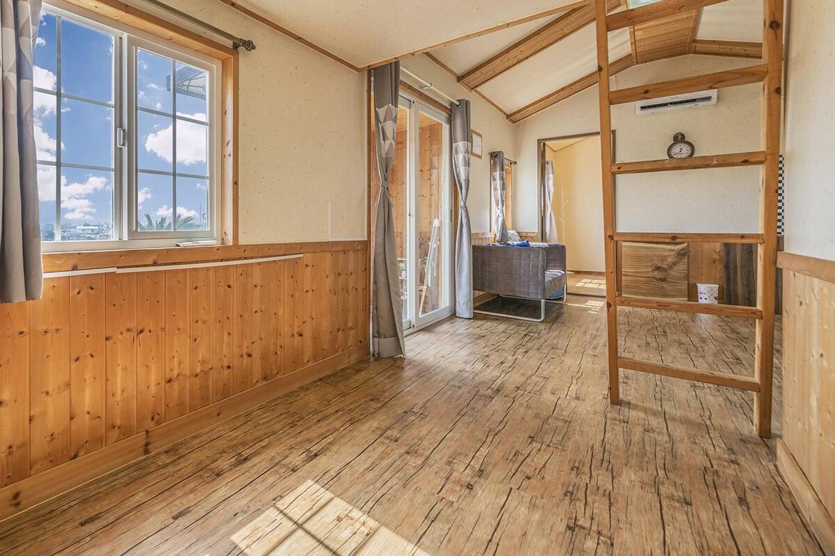 Une pièce avec des lambris en bois, un lit, un bureau et une échelle.