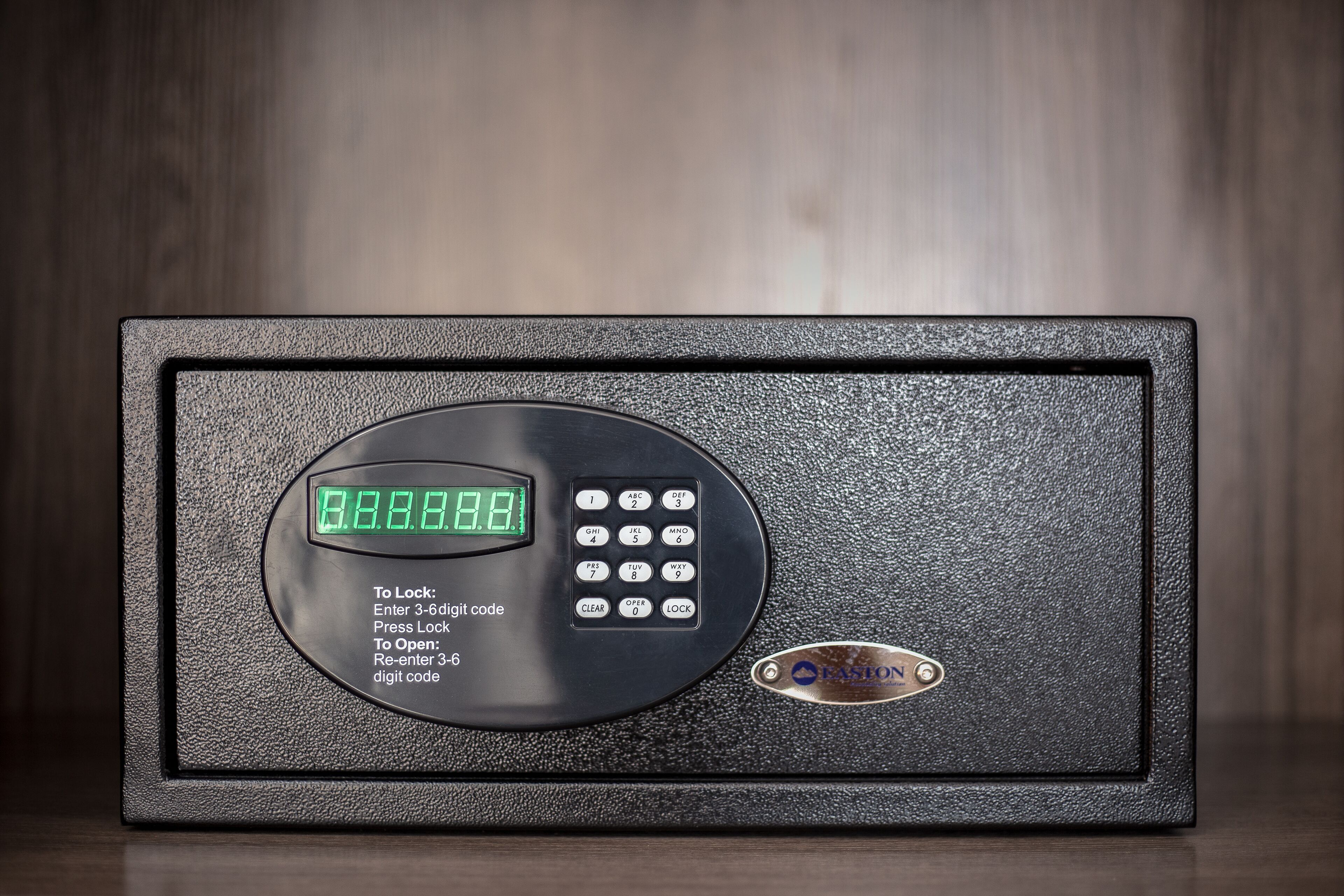 Een zwarte kluis met een digitaal slot, een keypad en een logo.