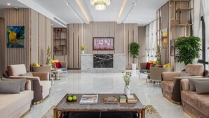 A spacious living area with a marble fireplace, modern furniture, and a large chandelier.