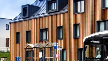 A modern building with a wooden facade and a bus stop shelter.