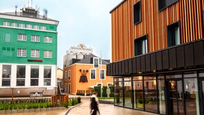 A modern building with a green facade, a wooden structure with vertical lines, and a sign for Brasserie Nationale. - De Brauhotel (Käerjeng)