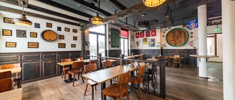 Un restaurante con mesas y sillas de madera, luces colgantes y adornos en las paredes.