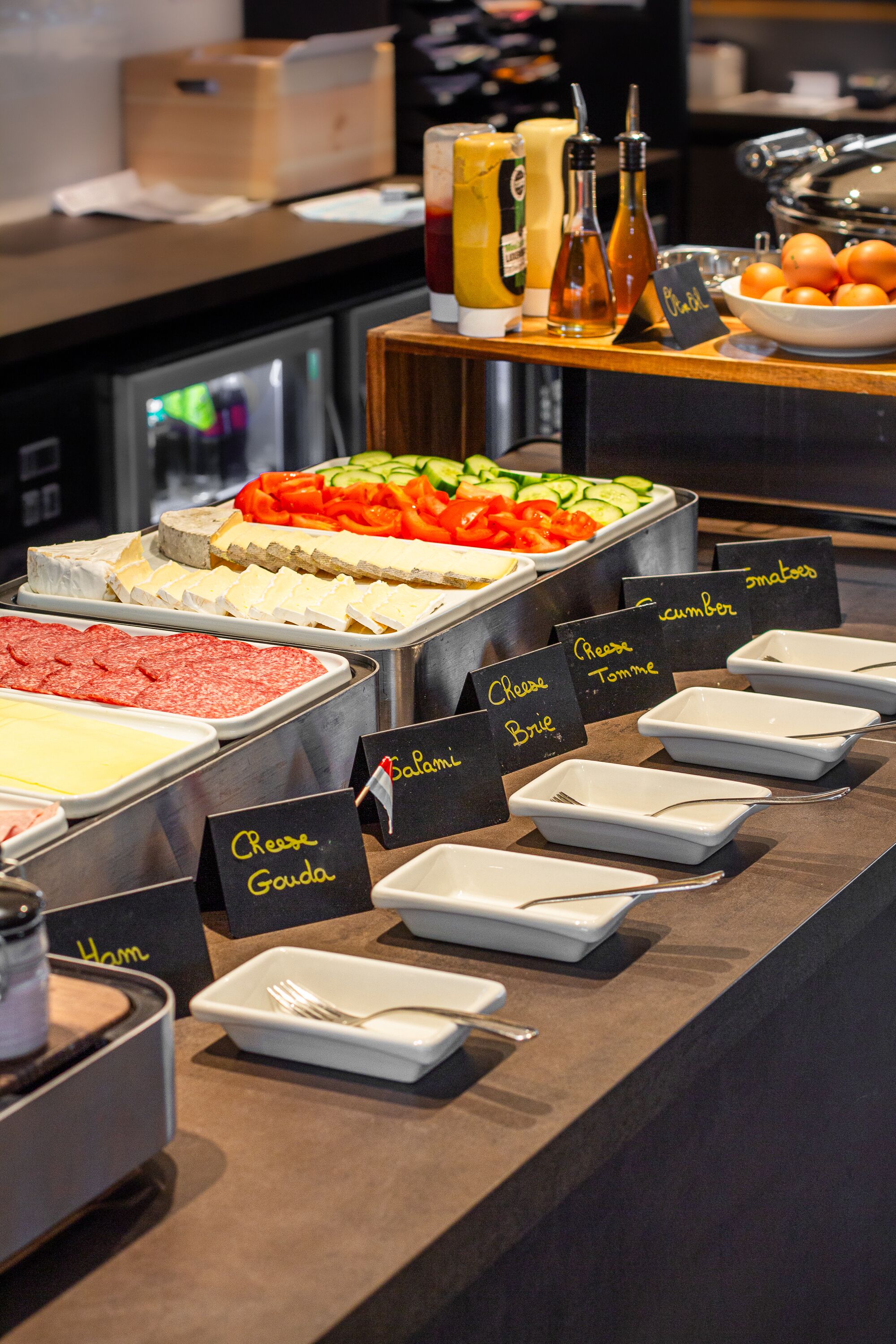 A buffet with various food options labeled, including ham, cheese, and tomato.