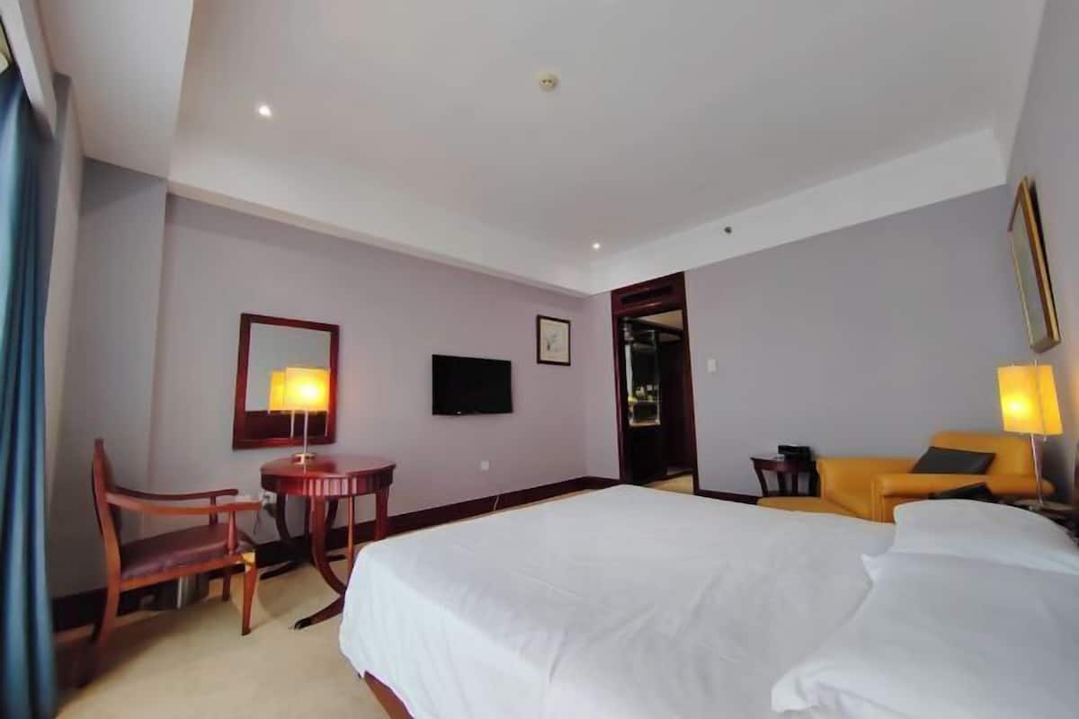 Une chambre d’hôtel avec un grand lit, un bureau avec une lampe, une chaise et un canapé.