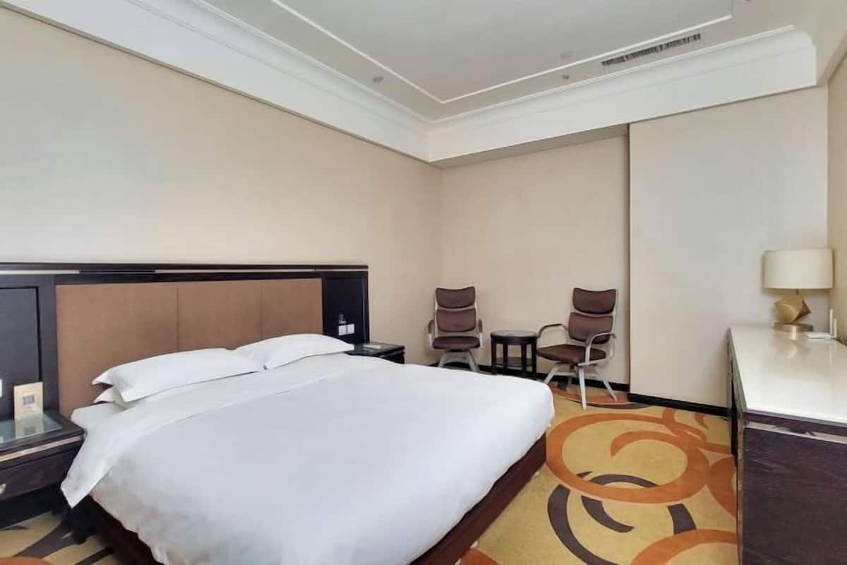 Une chambre d’hôtel avec un grand lit, un bureau, deux chaises et une petite table.