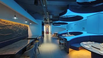 A modern restaurant interior with a long counter, seating area, and a distinctive ceiling design.