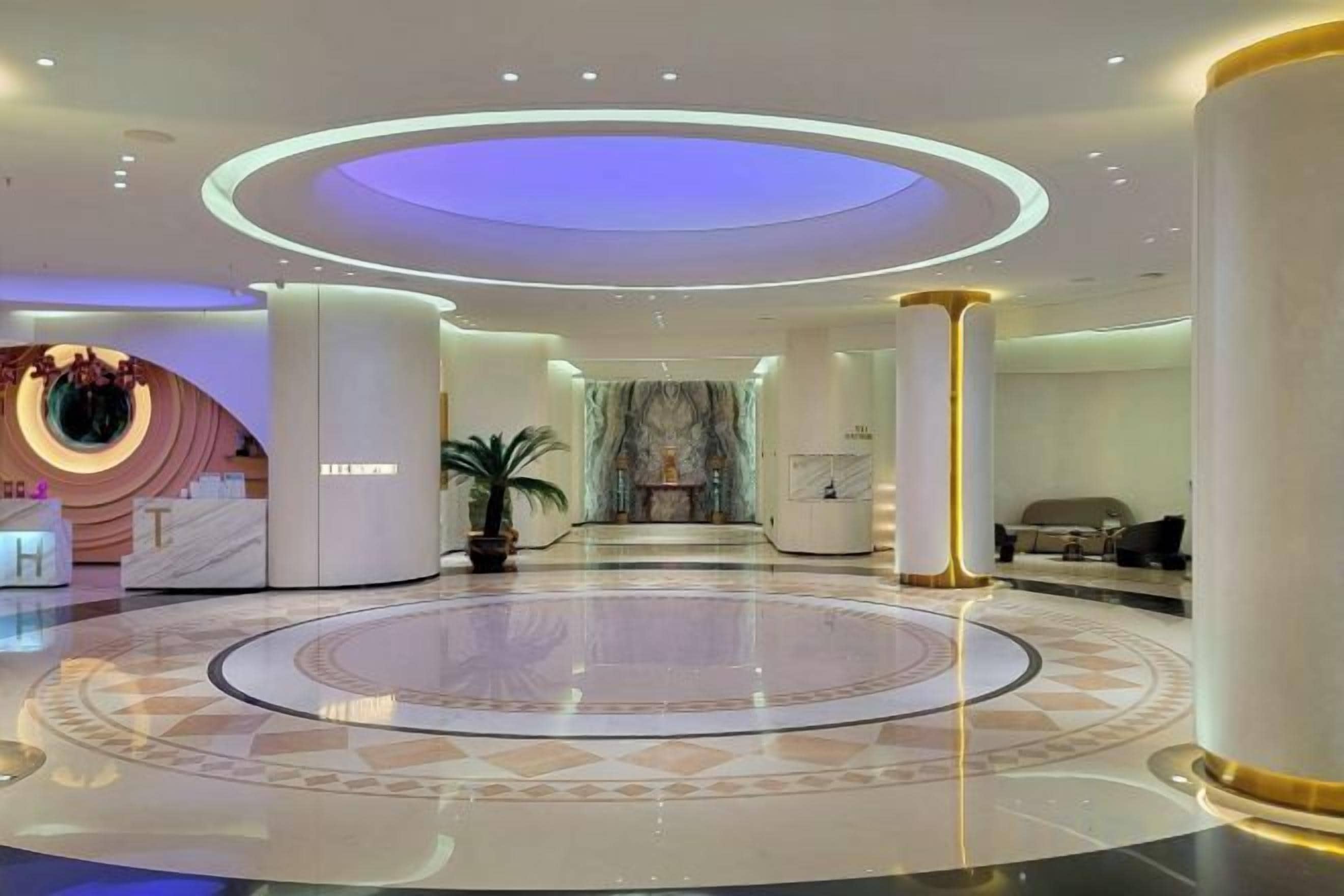 A spacious lobby with a circular marble floor, a reception desk, and a seating area.