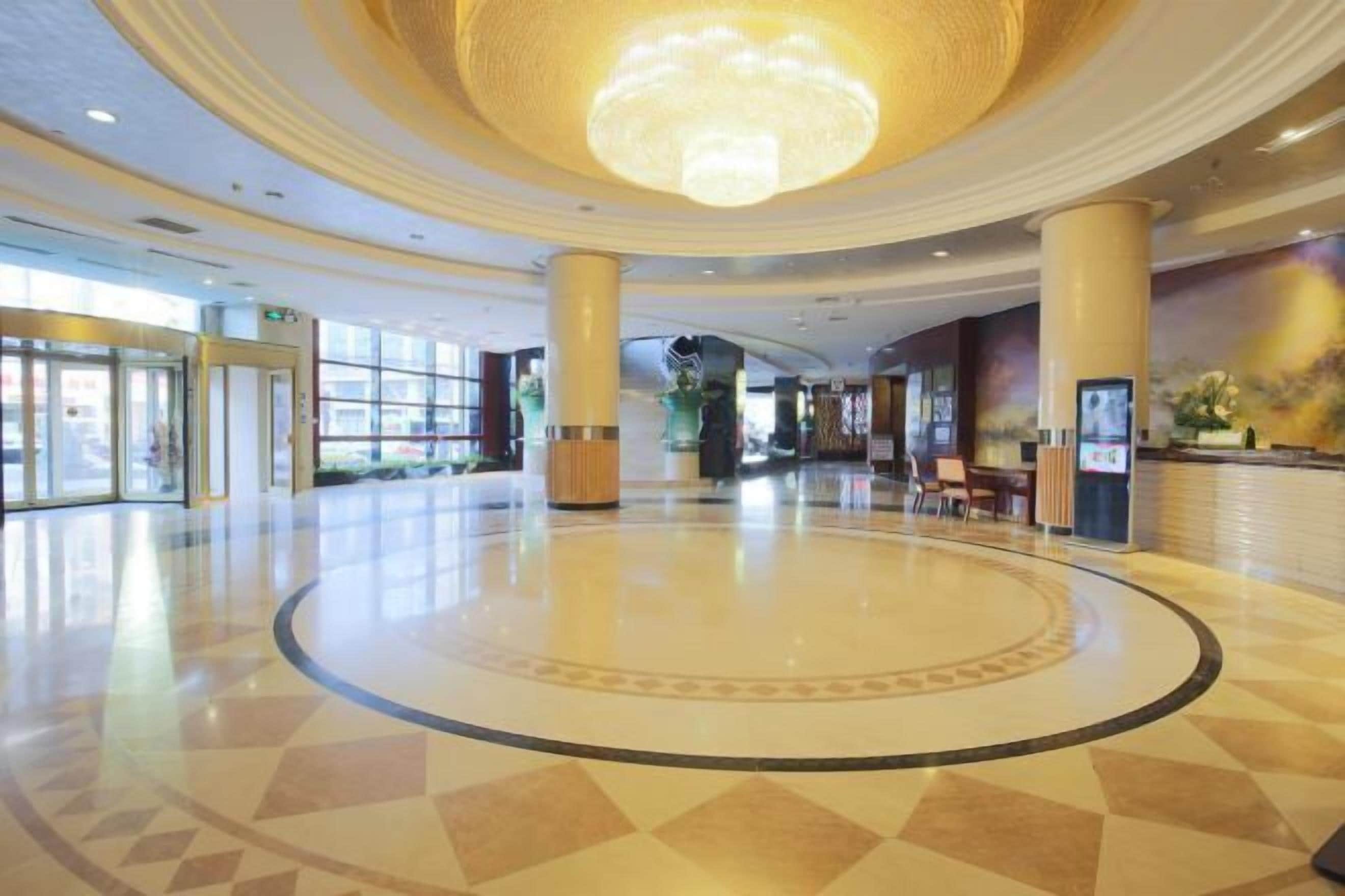 A spacious lobby with a central circular area, large columns, and a chandelier.