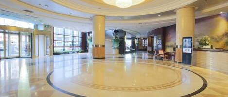 A spacious lobby with a central circular area, large columns, and a chandelier.