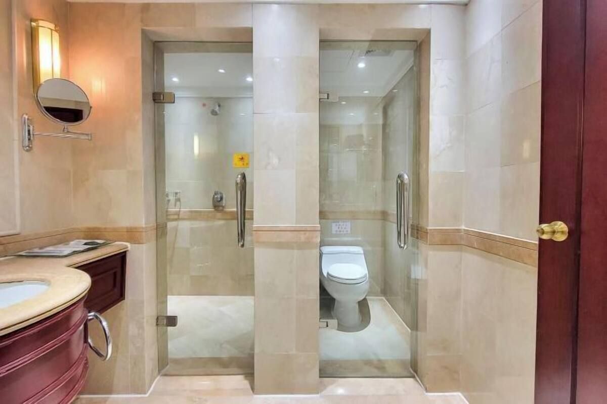 Ein modernes Badezimmer mit einer Duschkabine, einer Toilette und einem Waschtisch mit Spiegel.