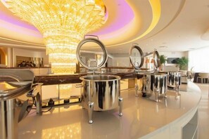 A luxurious hotel lobby with a grand chandelier, a polished reception desk, and a modern interior design.