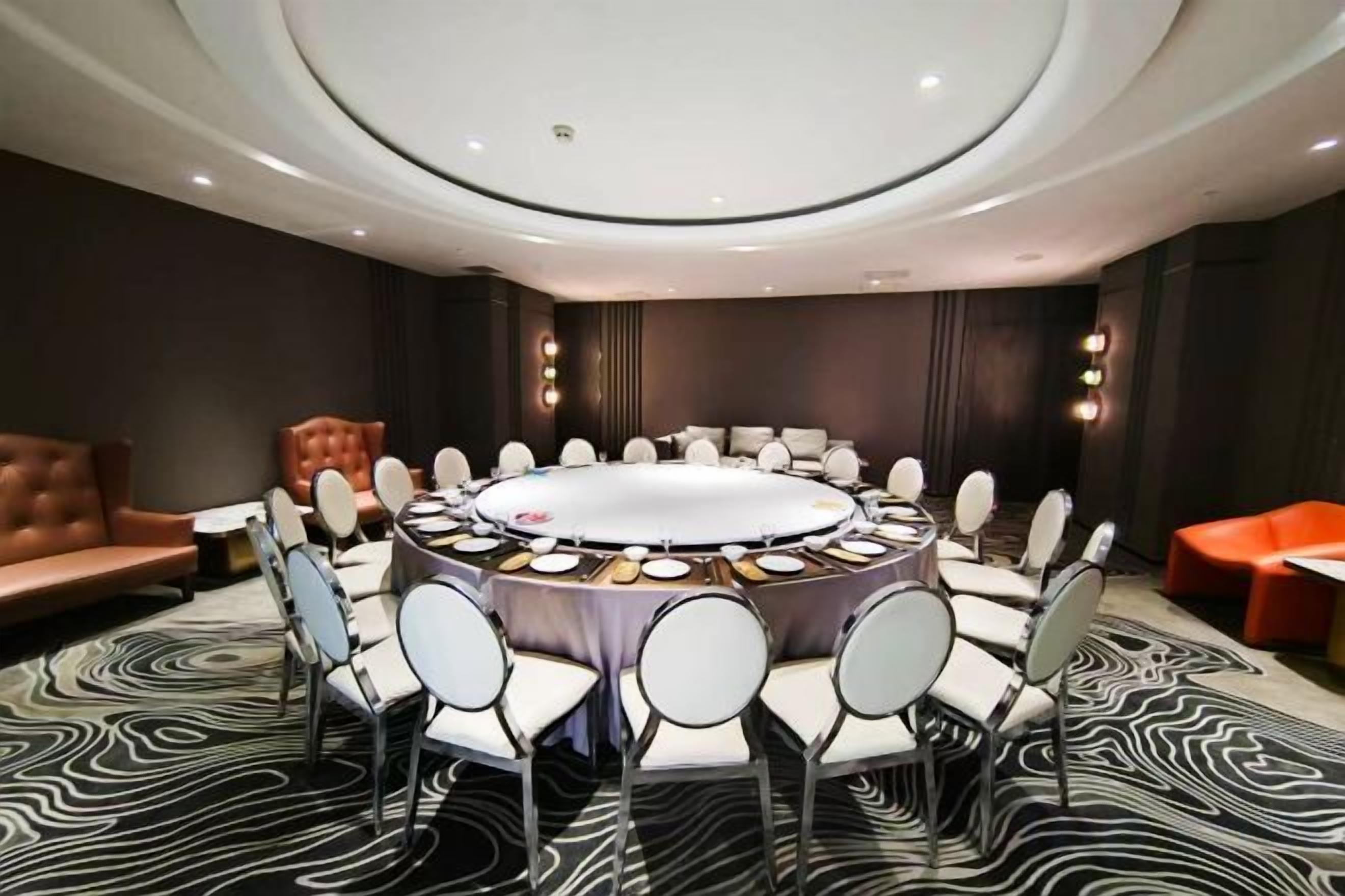 Un salón de conferencias con una mesa redonda, sillas y una alfombra con estampado de cebra.