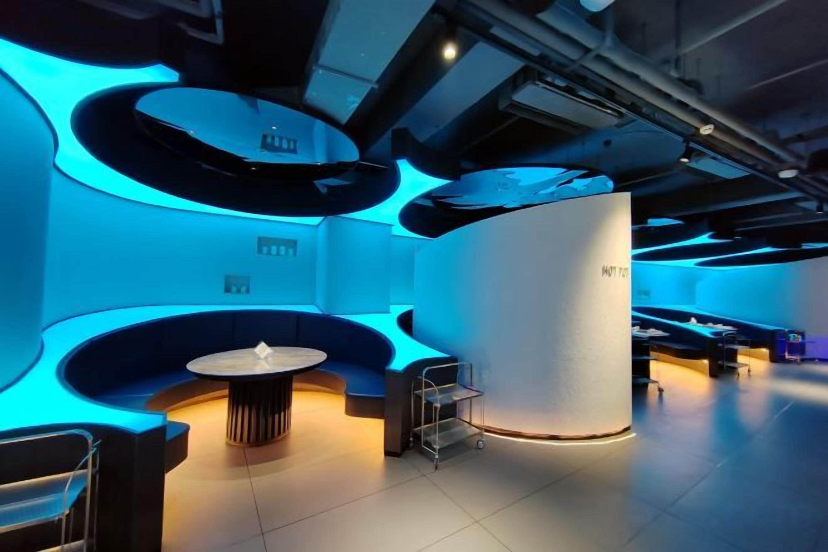 Un interior moderno con una zona de estar circular, una mesa central y una columna cilíndrica.