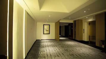 Un pasillo de hotel con piso de madera, obras de arte enmarcadas en la pared y puertas que dan a las habitaciones.