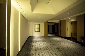 A hotel corridor with a wooden floor, framed artwork on the wall, and doors leading to rooms. - Ying Kou Hua Tian Hotel (Yingkou)