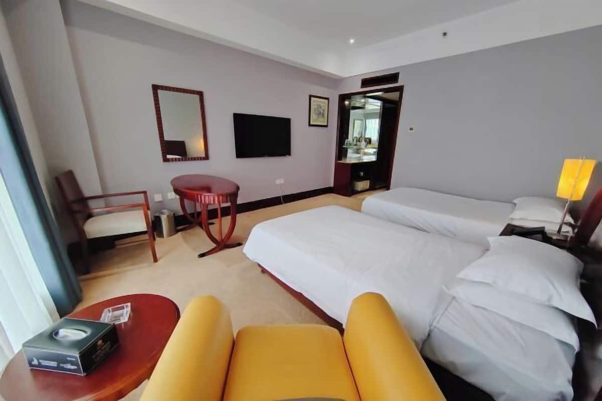 Une chambre d’hôtel avec un lit, une chaise, une petite table, un téléviseur et un miroir.