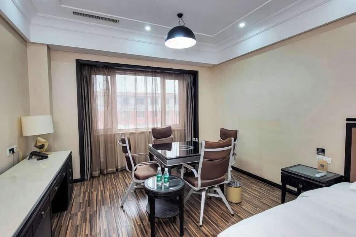 Une chambre d’hôtel avec un lit, un bureau, une chaise, une table et une fenêtre avec des rideaux.