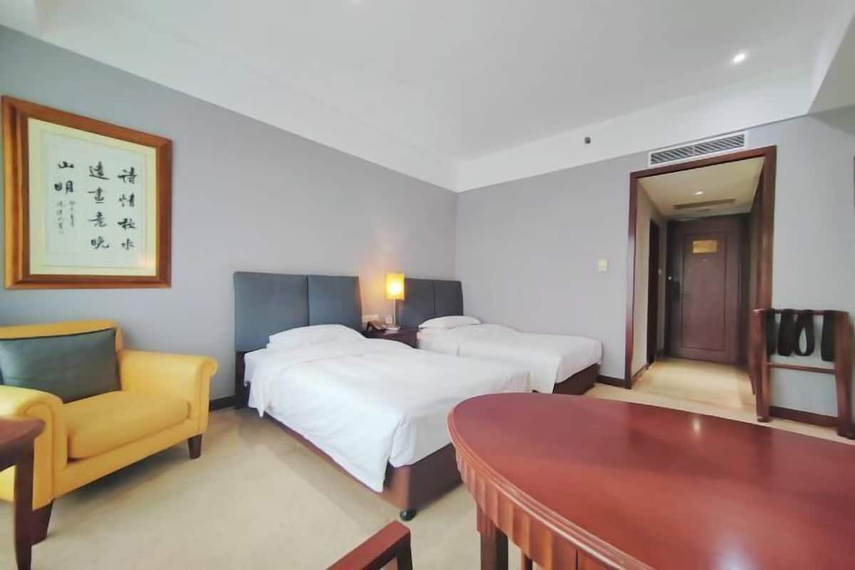 Une chambre d’hôtel comprenant un lit, des tables de chevet, un bureau, une chaise, un canapé et une œuvre d’art encadrée accrochée au mur.