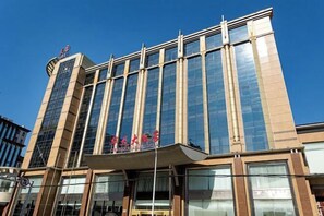 A modern hotel with a prominent glass facade and a sign indicating it is a hotel.