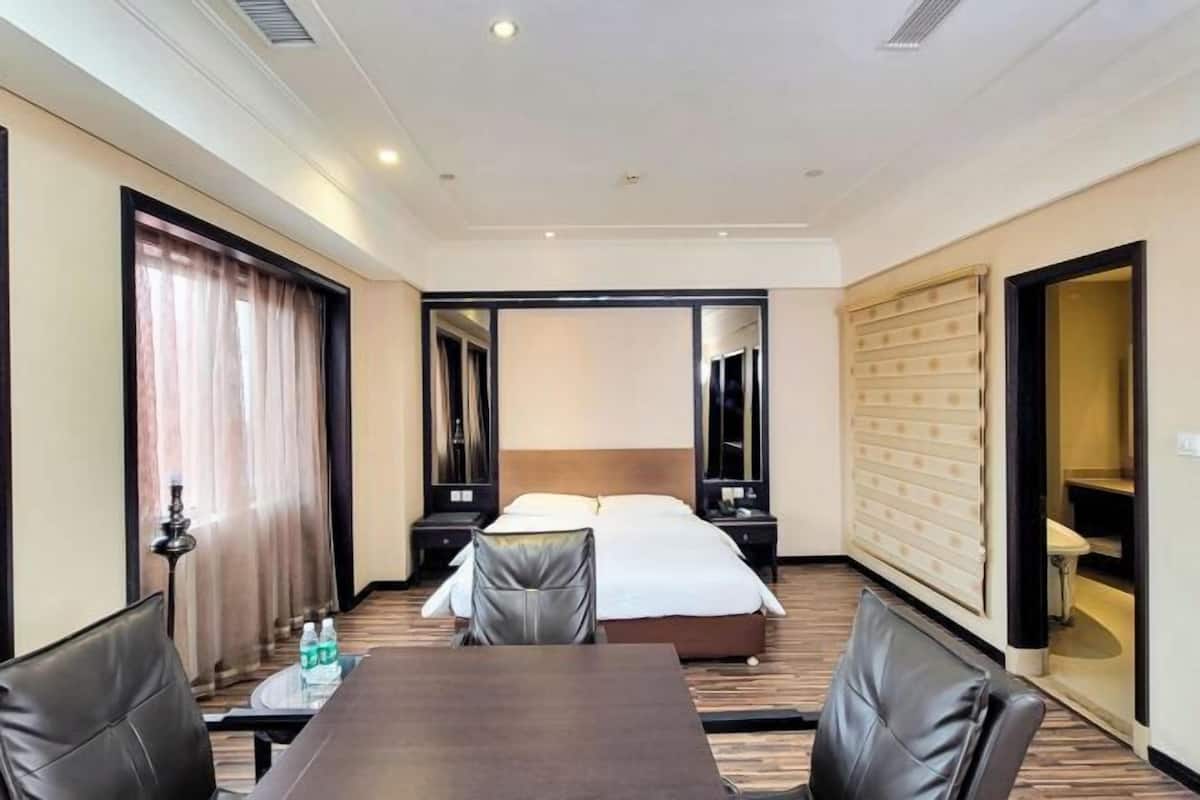 Une chambre d’hôtel comprenant un lit, un bureau avec des chaises, un miroir et une armoire.
