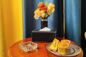 A table with a vase of flowers, a tissue box, and a plate with muffins.