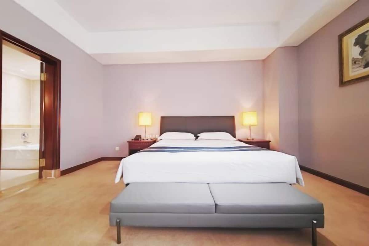 Une chambre d’hôtel avec un lit, des lampes de chevet, une table de nuit et une grande fenêtre.