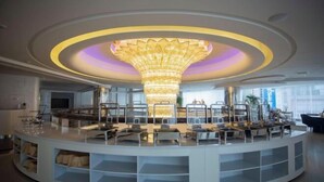 Een moderne, ronde receptiebalie met een centrale kroonluchter, glazen vitrines en een zithoek langs de rand.