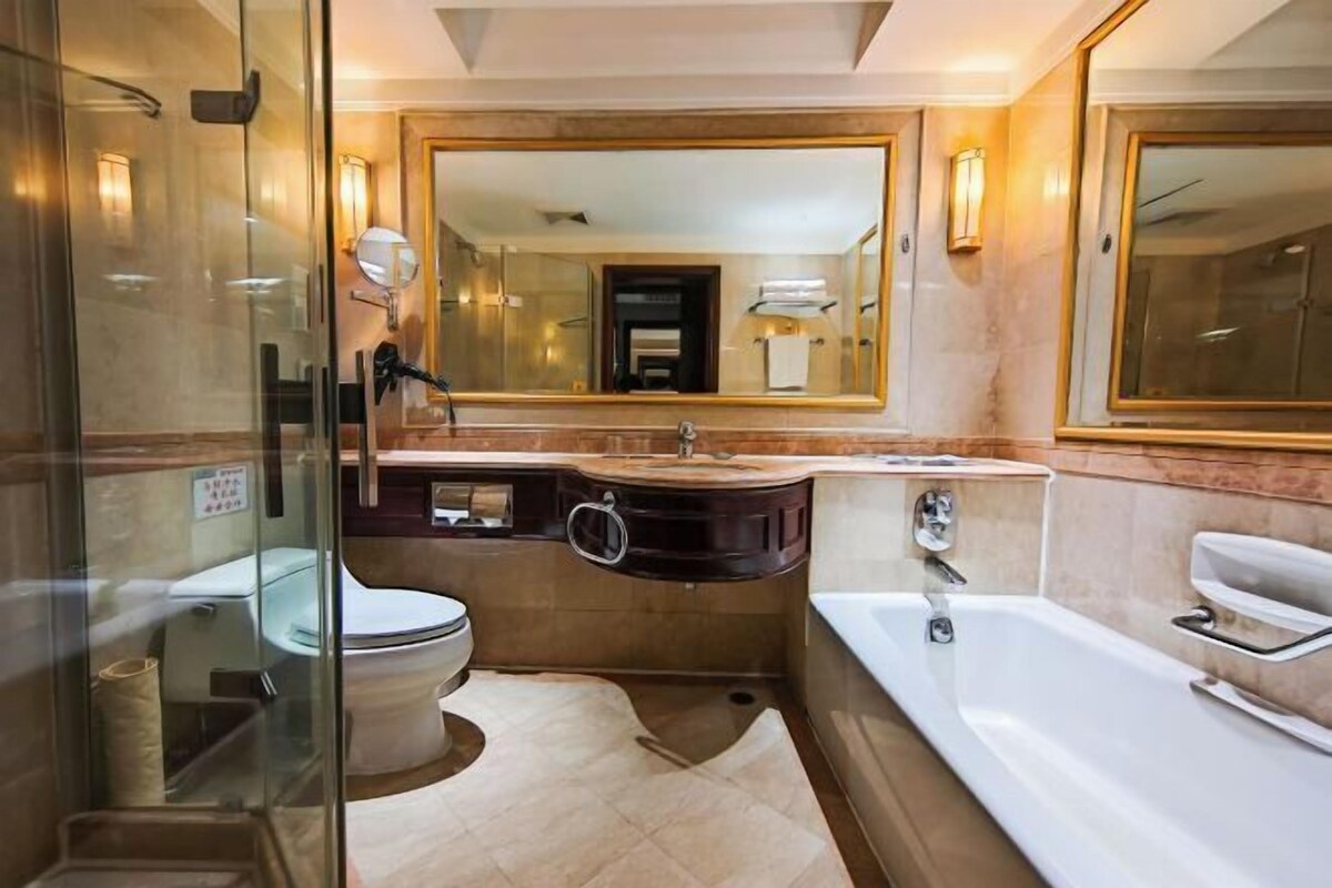 Une salle de bain moderne dotée d’une douche à parois de verre, d’un grand miroir, d’une baignoire et d’un meuble-lavabo avec un évier et un miroir.
