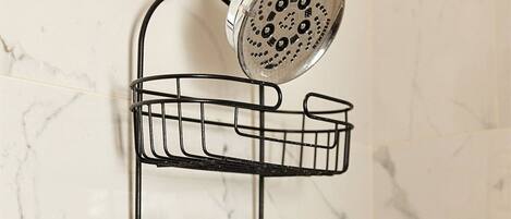 A bathroom with a shower, a marble wall, and a black metal shelf holding bottles.