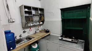 A compact kitchen with a sink, stove, and shelves for dishes. - Pre Independence 2 BHK Bungalow,dalhousie,himachal (Dalhousie)