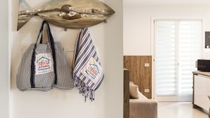 Une pièce dont le mur est orné d’une grande décoration représentant un poisson, avec deux sacs à rayures suspendus en dessous, et une porte en bois à l’arrière-plan.