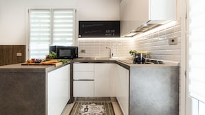 Une cuisine moderne avec des meubles blancs, un micro-ondes noir et un tableau noir sur lequel est écrit du texte.