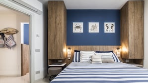Une chambre à coucher avec une couvre-lit à rayures, une tête de lit en bois et des œuvres d’art accrochées au mur.
