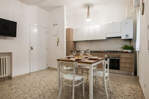 A modern kitchen with white cabinets, a built-in oven, and a gas stove. There is a dining table with chairs and a small plant on the counter. - Nettuno 3 - Two Bedroom Apartment, Sleeps 6 (Cattolica)